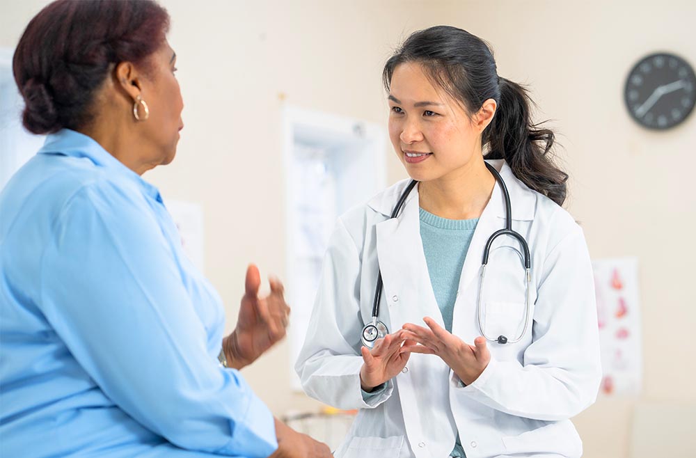 Female physician in lab coat talking to female patient